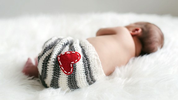gassy baby, photo shoot of newborn baby lying with heart blanket around waist